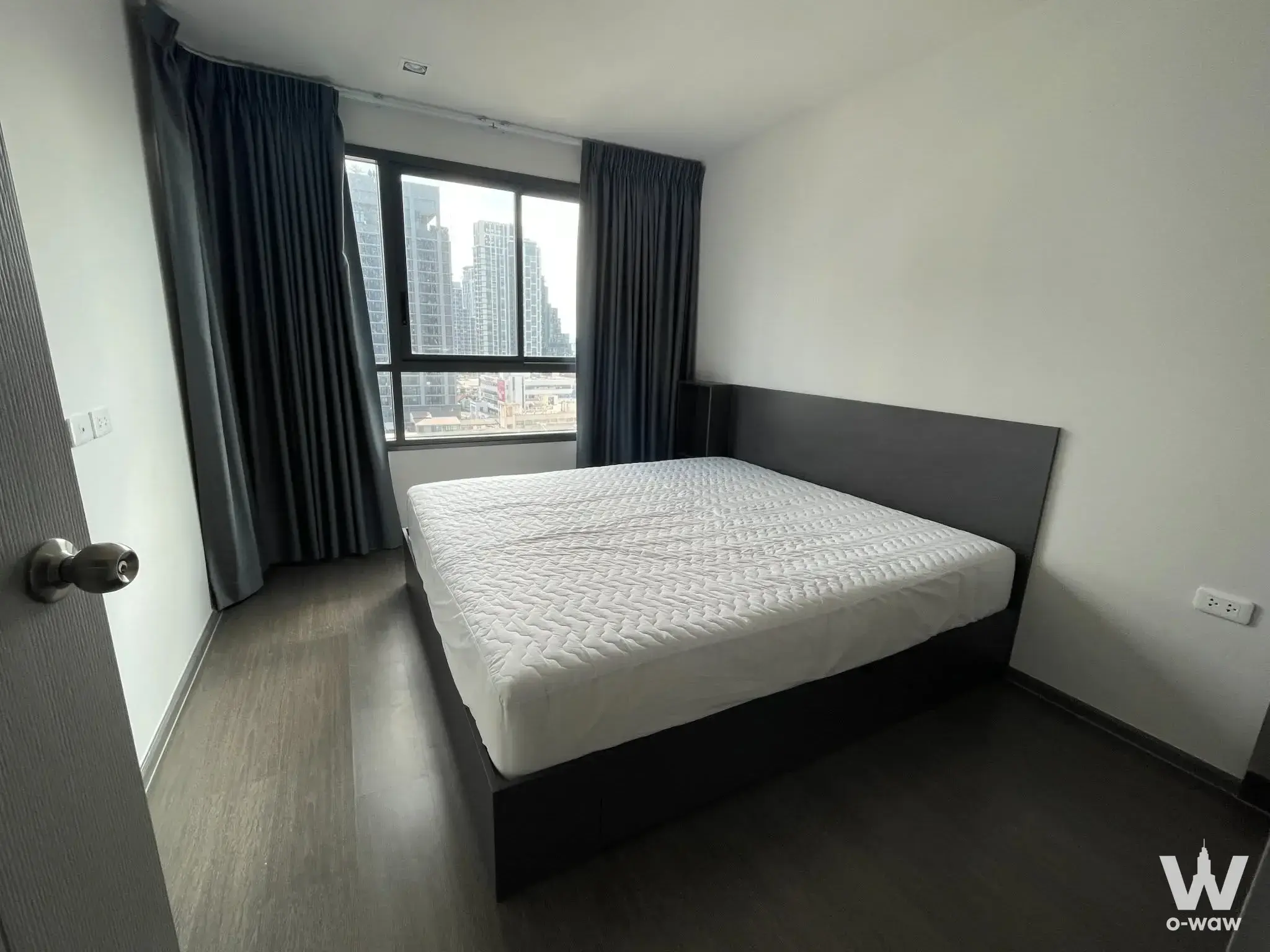 Sparsely furnished bedroom in Ideo Phaholyothin Chatuchak with city skyline view and minimalist design