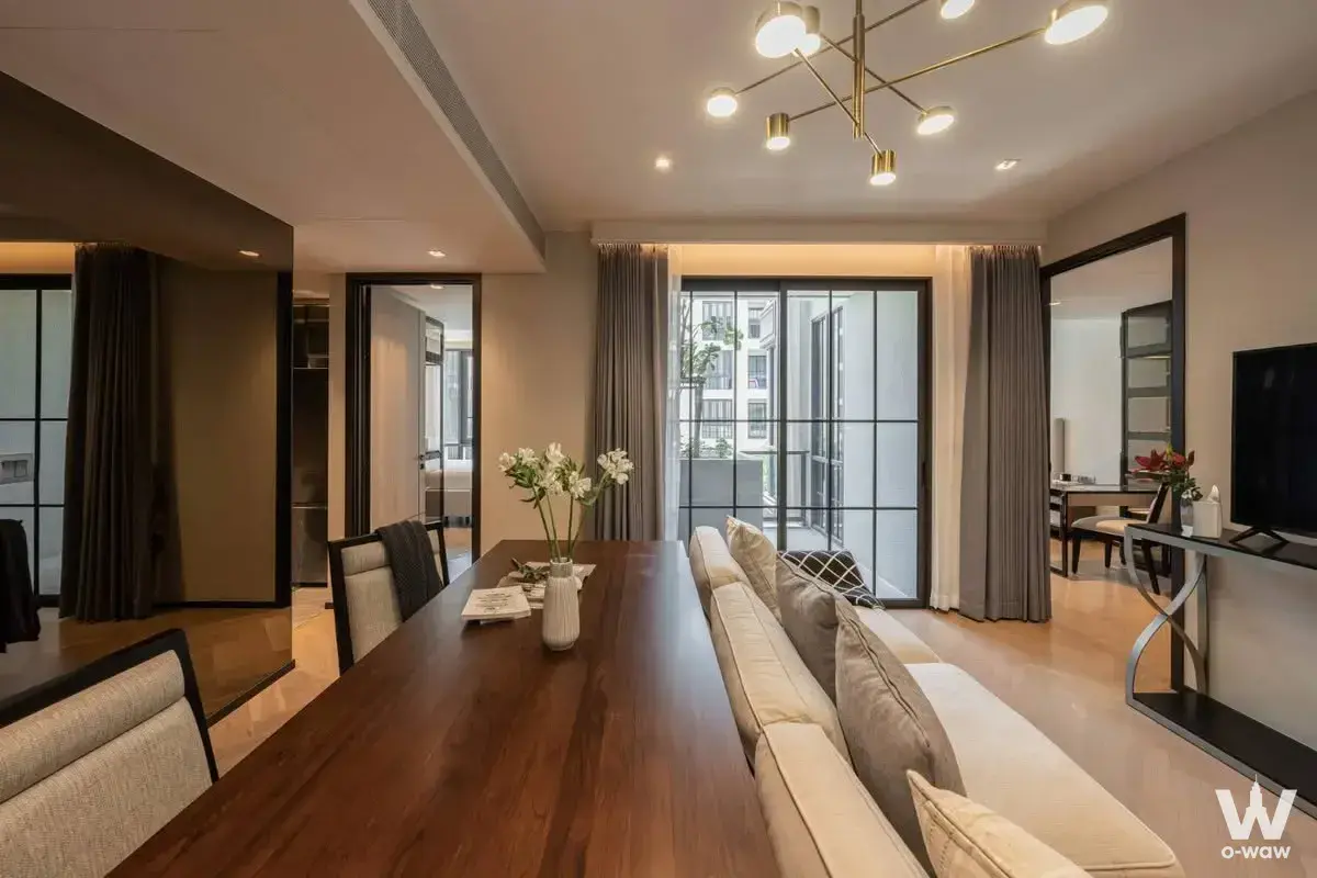 Modern living room with walnut dining table and balcony access in 2-bed condo for rent at The Reserve Sukhumvit 61