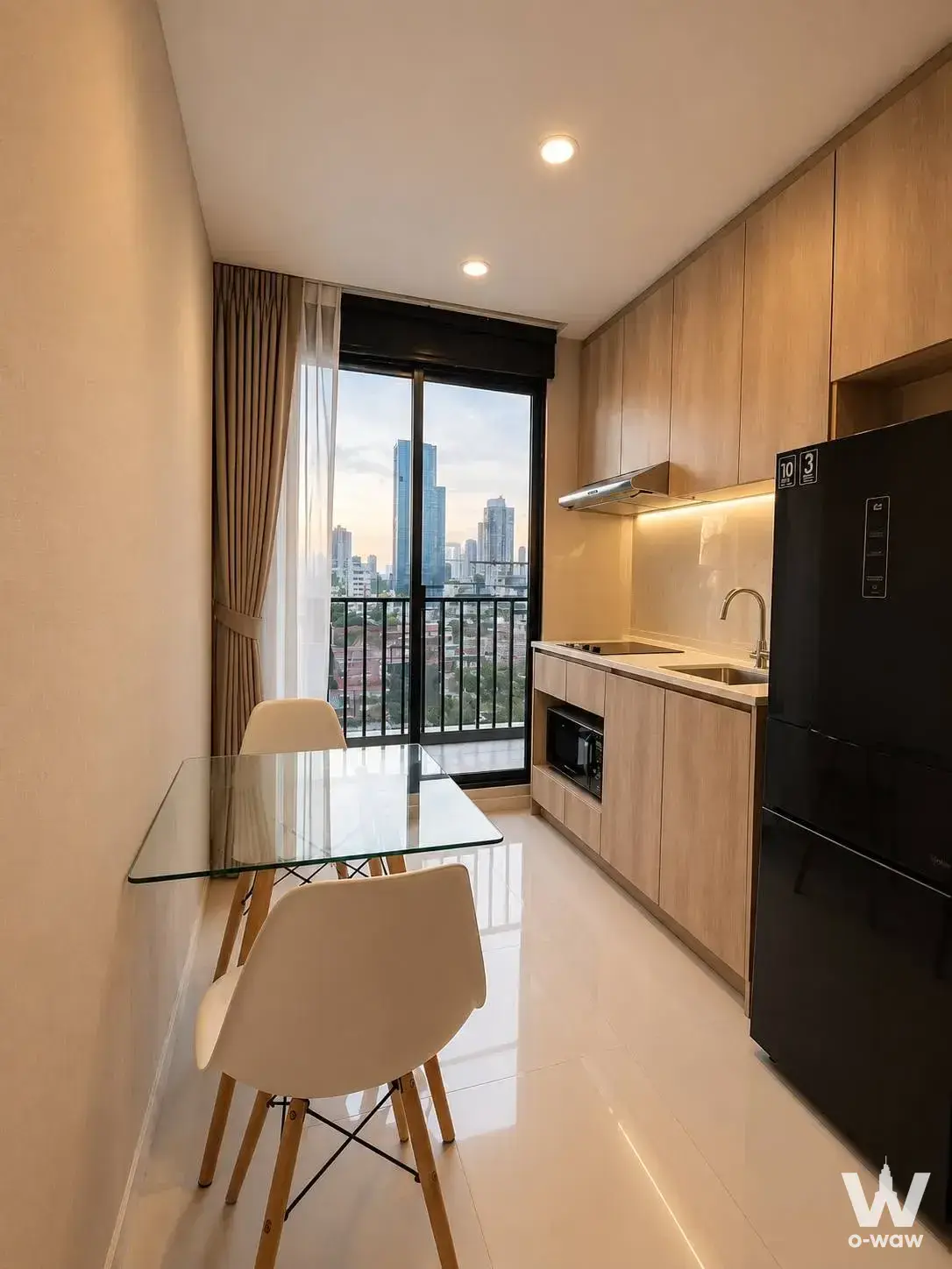 The 1-bed IKON Sukhumvit 77 condo for sale has an open-plan kitchen, dining area and a balcony view
