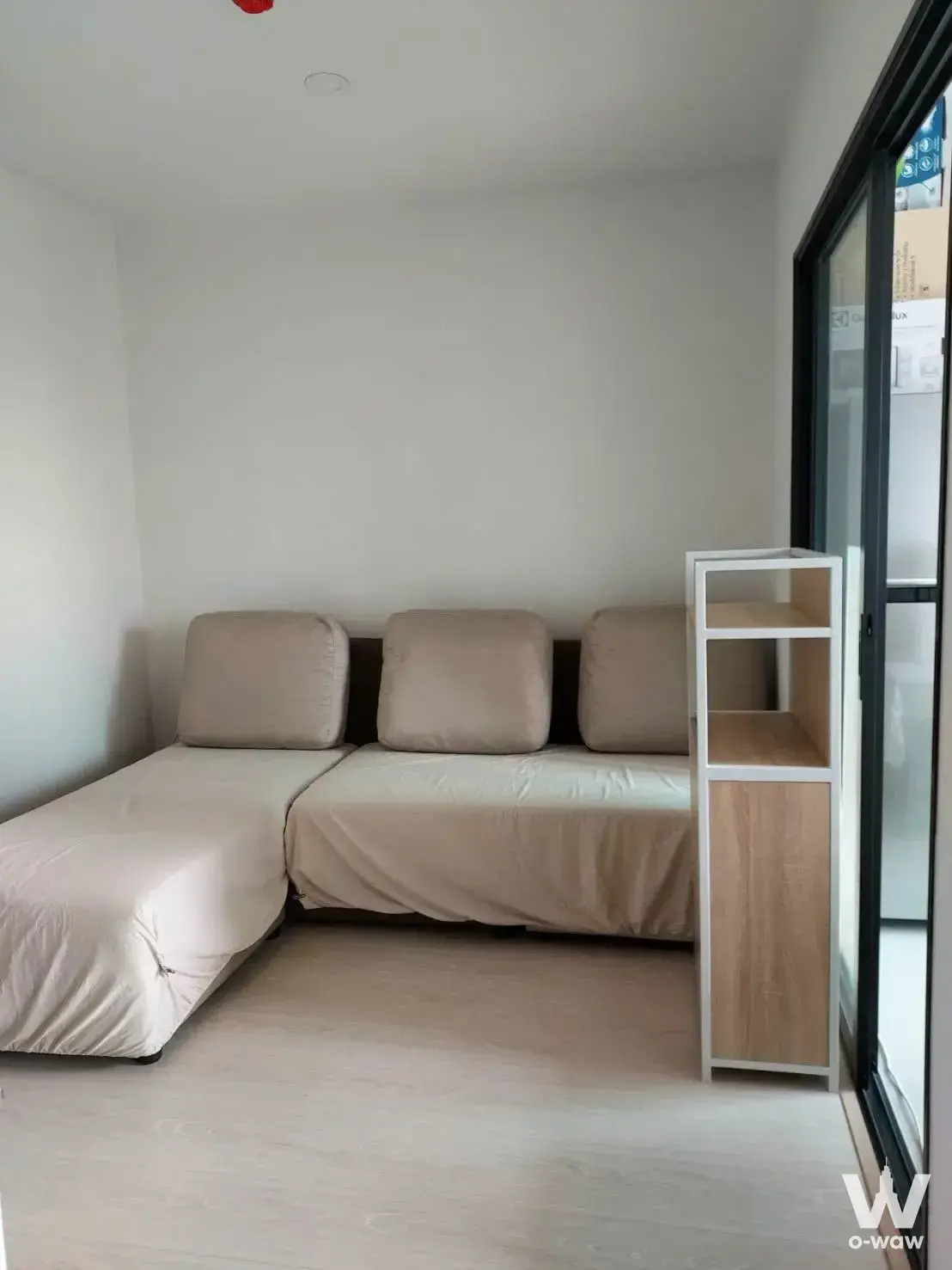 Minimalist living room with beige sectional sofa and open shelving in ELIO DEL NEST 1-bed condo