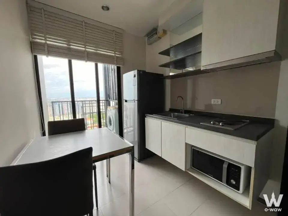 Modern kitchen in THE BASE Park West condo with white cabinets, dining set, and balcony access to washing machine