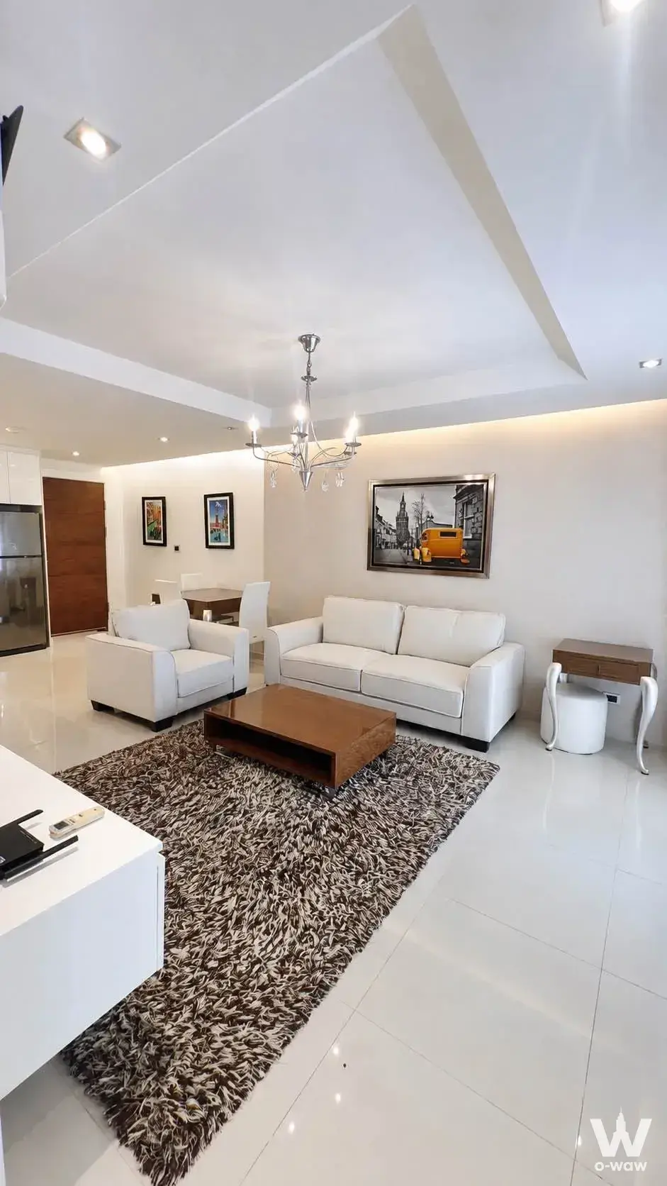 Living room in a 1-bed Sunset Boulevard Residence 1 condo rental with a white leather sofa and chrome chandelier