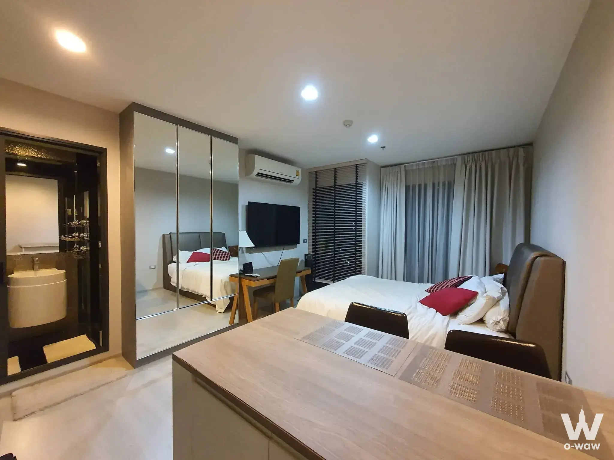 Master bedroom in Rhythm Sukhumvit 42 condo with grey upholstered headboard and mirrored wardrobe doors