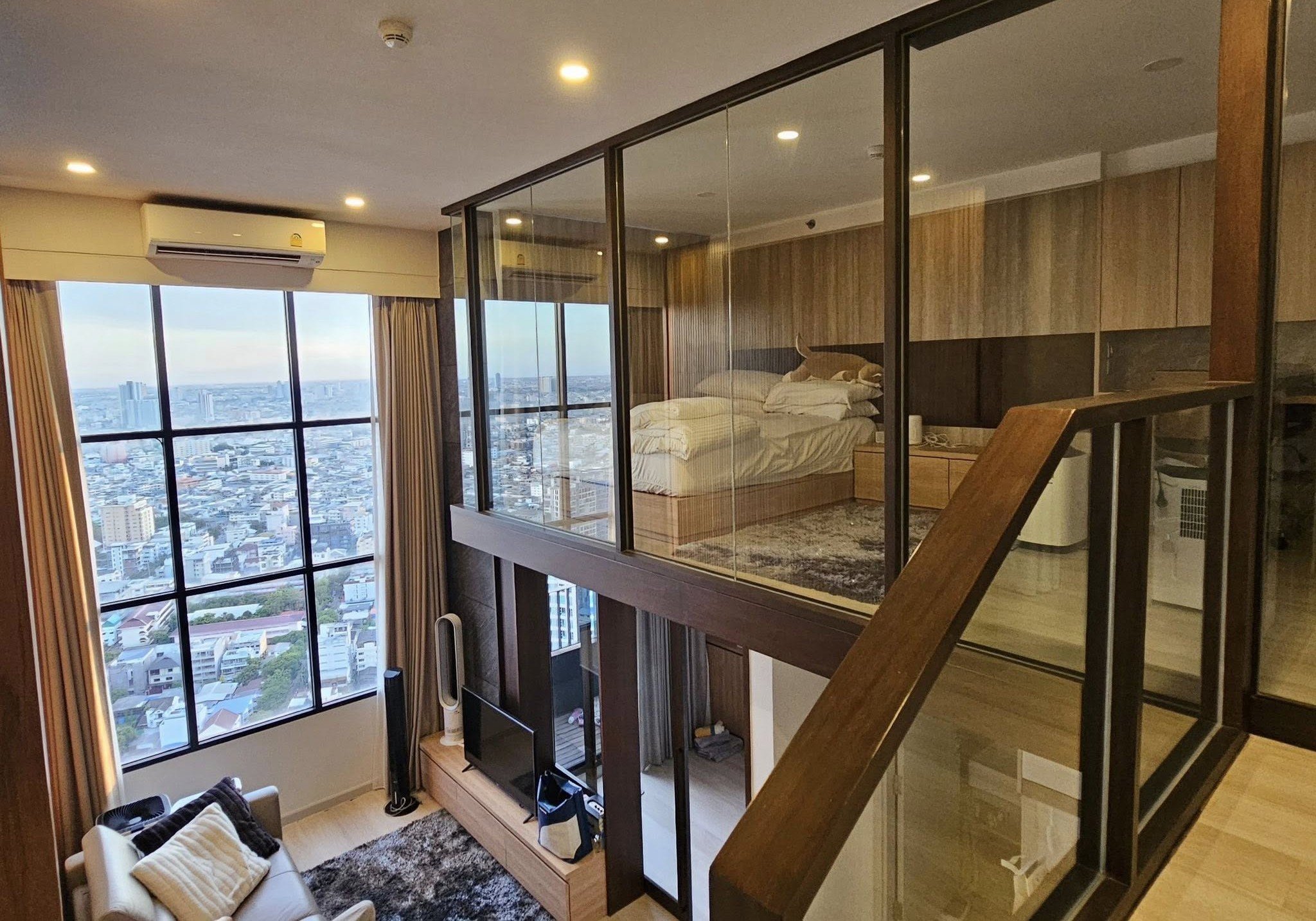 Duplex loft in KnightsBridge Prime Sathon with glass-enclosed mezzanine bedroom, city views, and open-plan living area