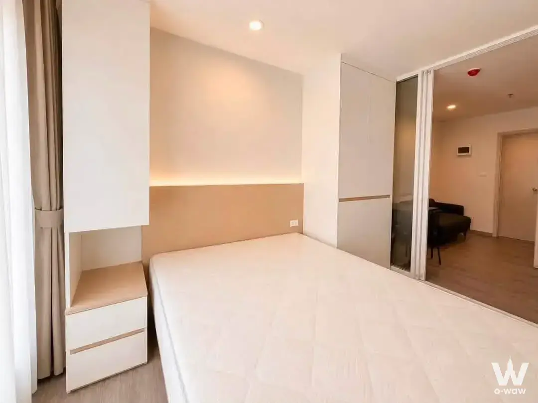 Modern bedroom in a Regent Home Wutthakat condo with tan wood headboard and mirrored wardrobe