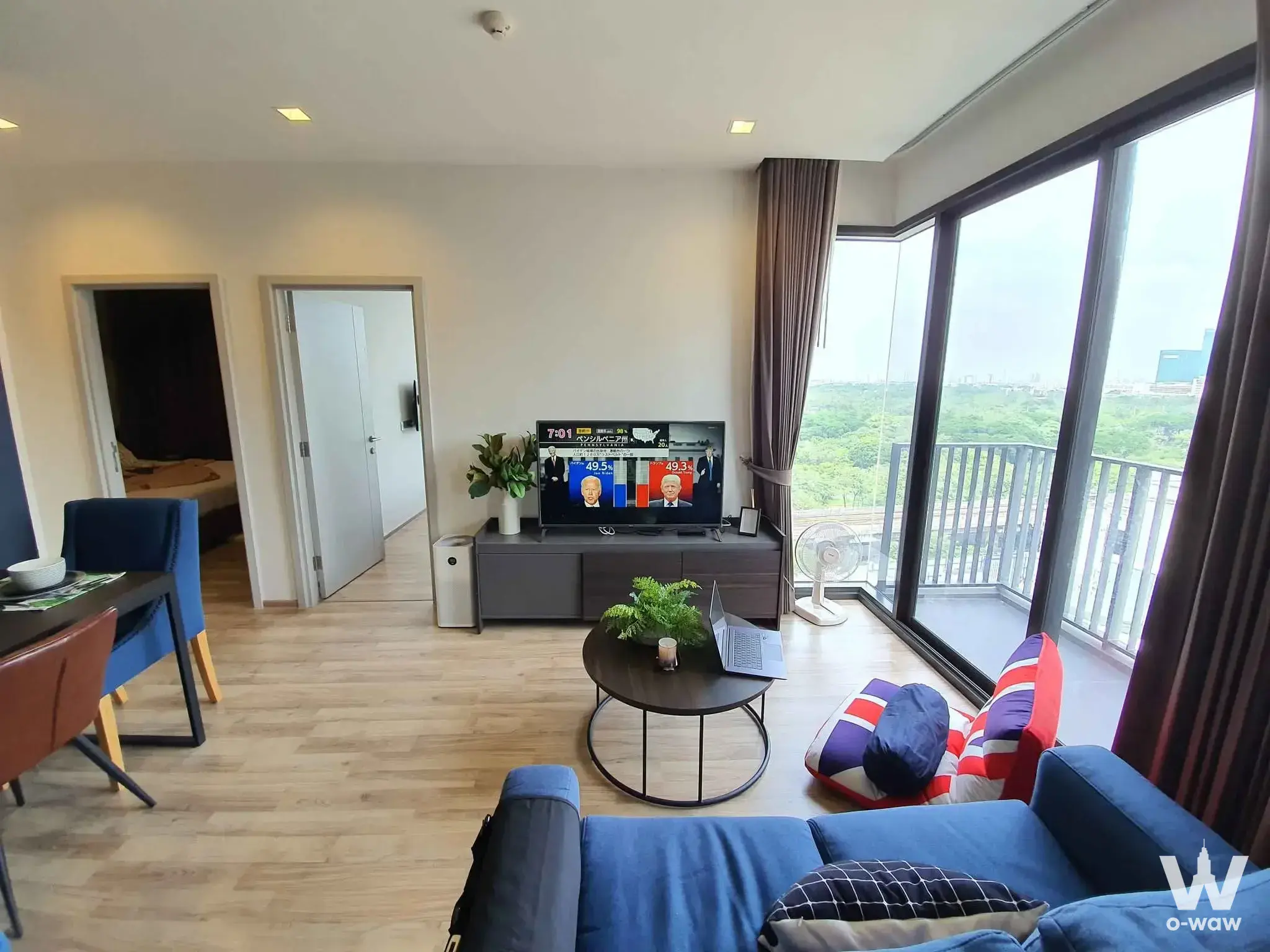 Living room with blue sofa and corner windows in a 2-bed condo for sale at THE LINE