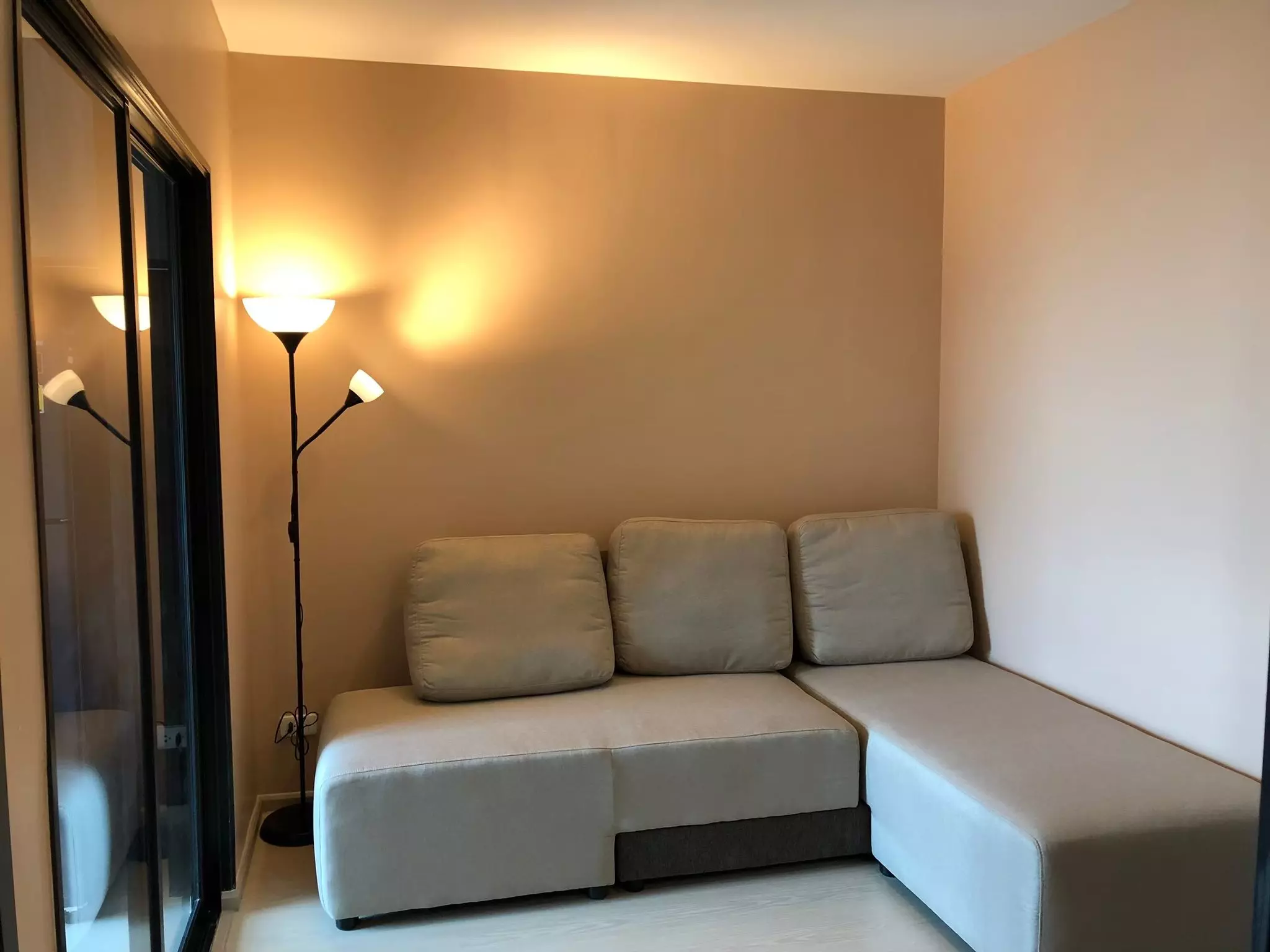 Modern living corner in ELIO DEL NEST featuring beige L-shaped sectional sofa and light wood-look laminate flooring