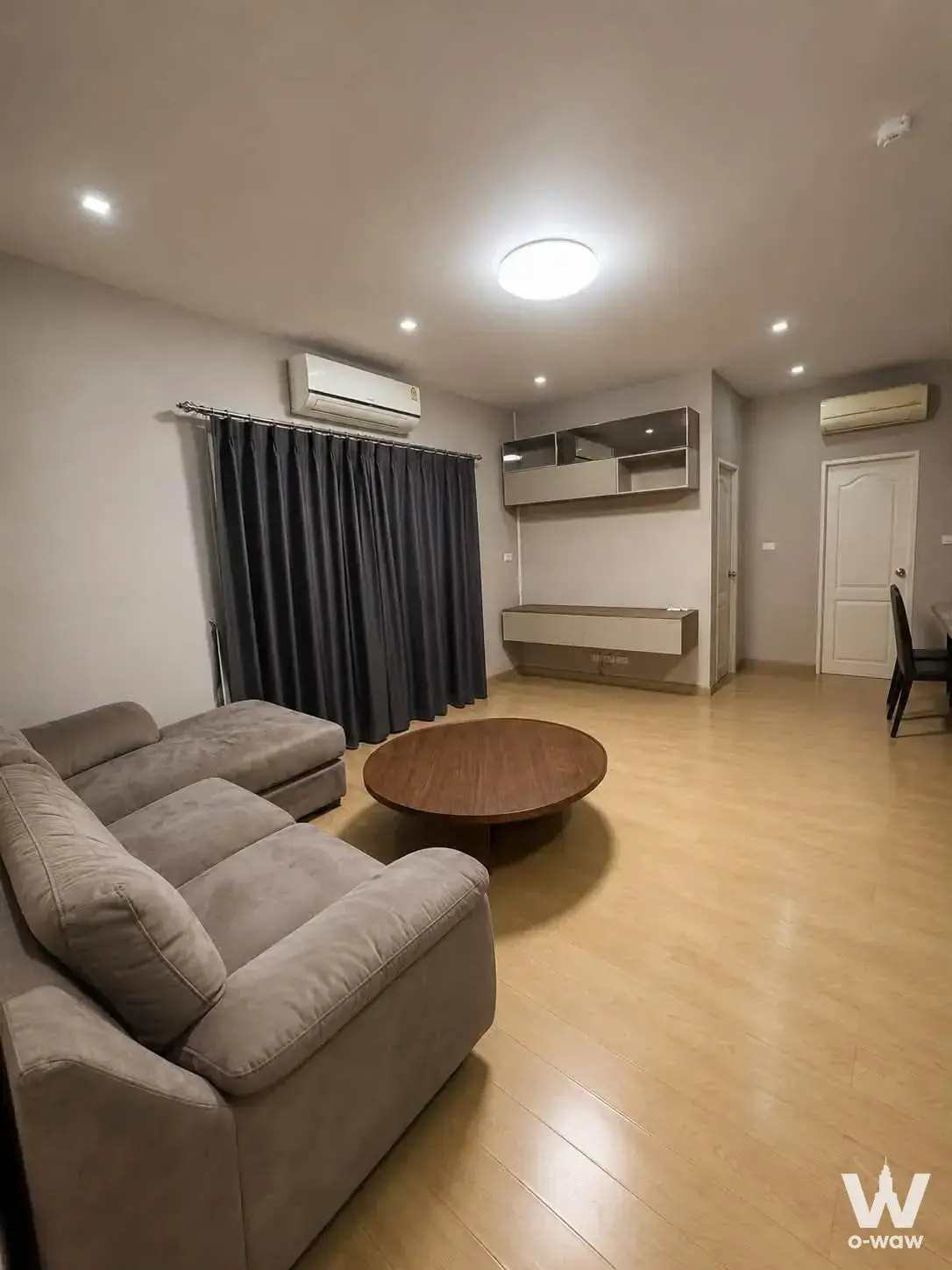 Villa Chaya 2-bed condo living room with grey sectional sofa, floating TV console, and neutral tones