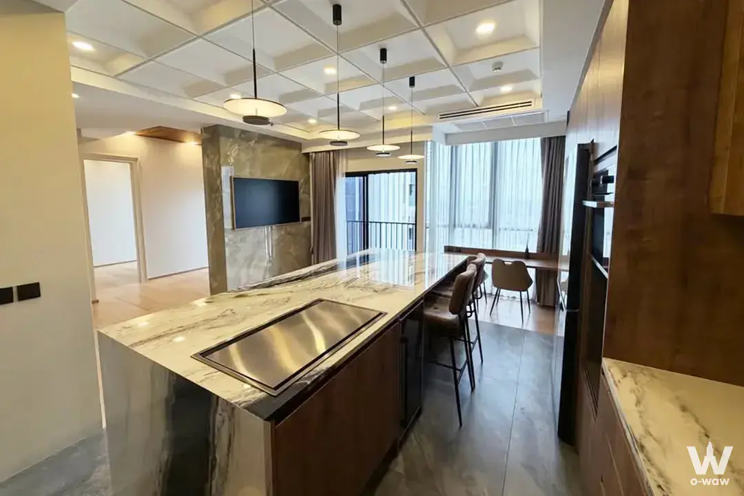 Open-plan kitchen in Park Origin Thonglor condo with marble island and dark wood cabinets