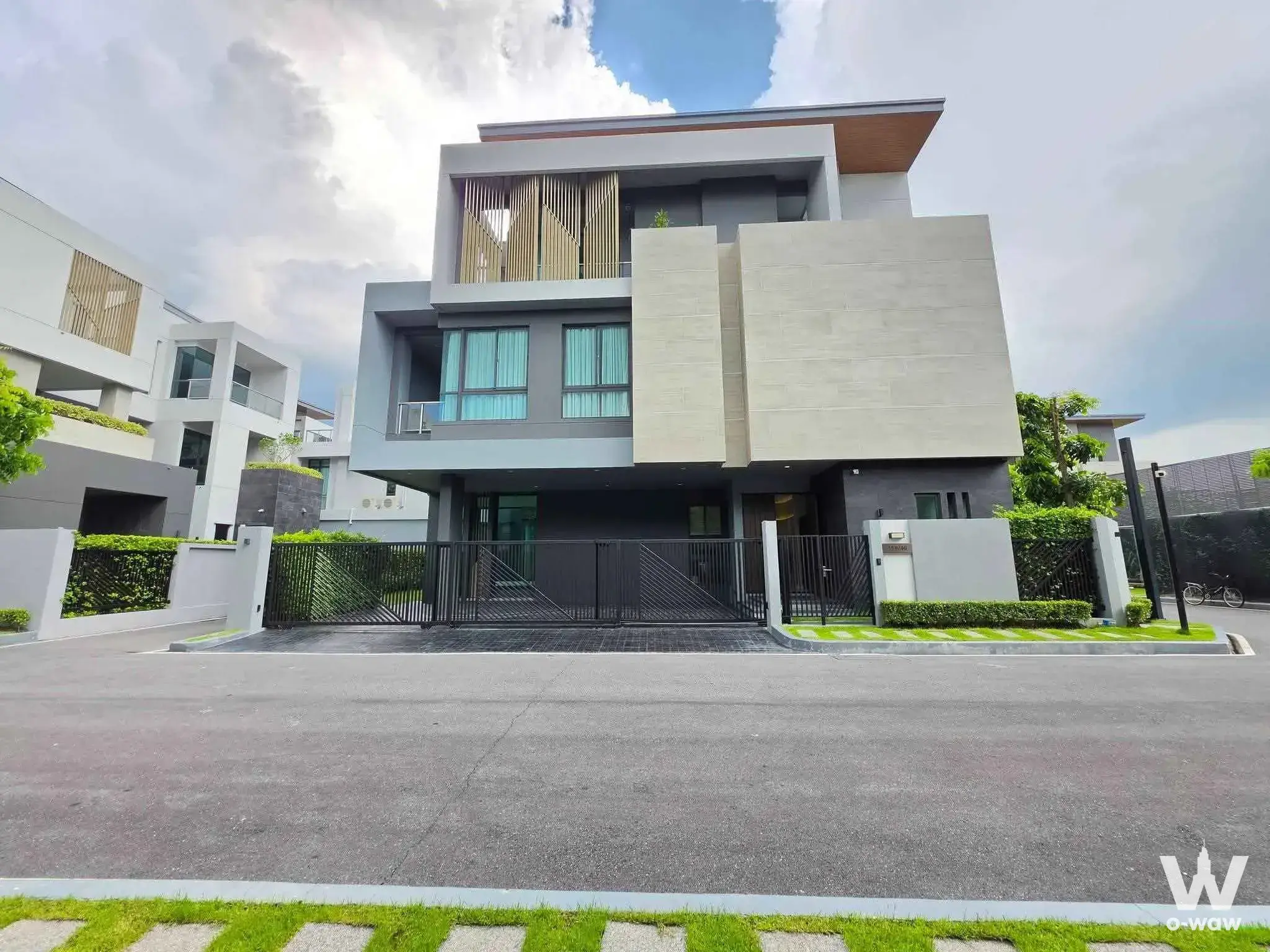 Dark charcoal grey villa exterior with wood-slat balcony at The Gentry Phatthanakan 2