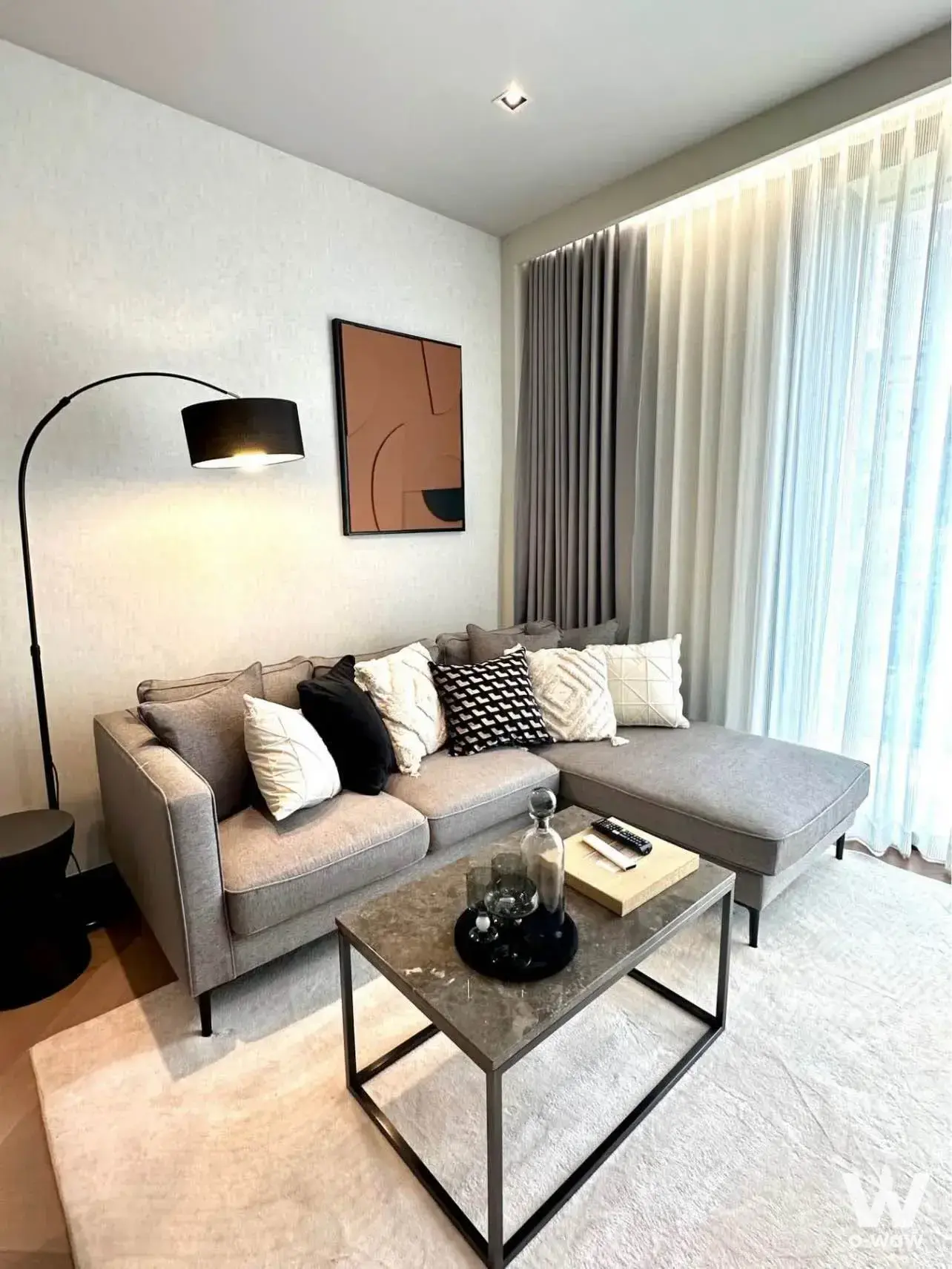 Bright living room in a 1-bed condo at THE RESERVE 61 HIDEAWAY featuring a grey sectional sofa and dark marble coffee table