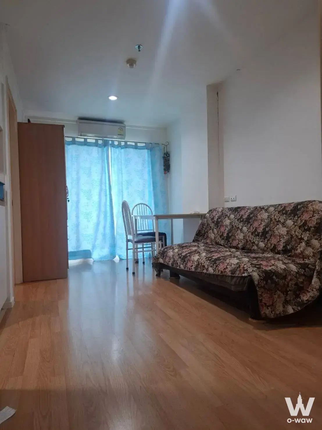 Furnished living room in Lumpini Ville Sukhumvit 71-2 featuring floral sofa, dining set, and wooden wardrobe