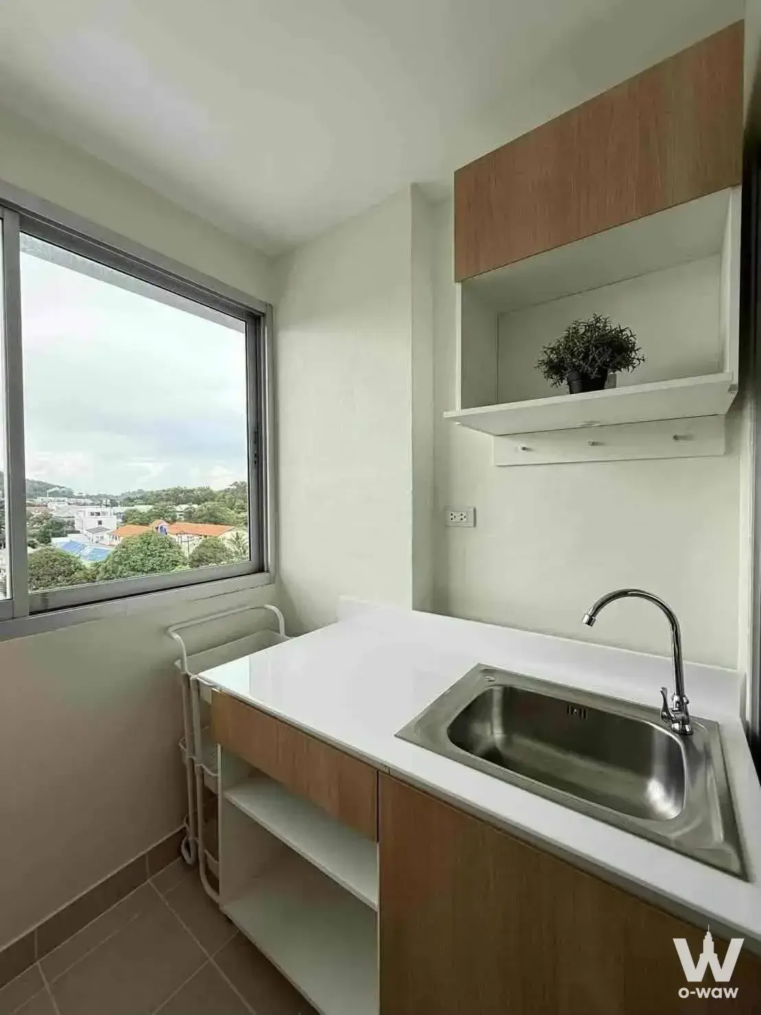 Compact kitchenette in a Supalai City Resort Charan 91 condo with white laminate counters and light wood cabinets