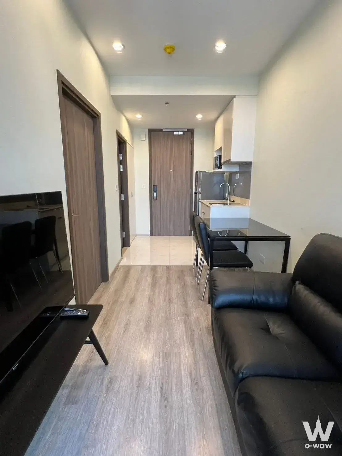 Modern studio condo for sale in Ideo Mobi Sukhumvit 66 featuring grey flooring, black leather sofa, and open layout