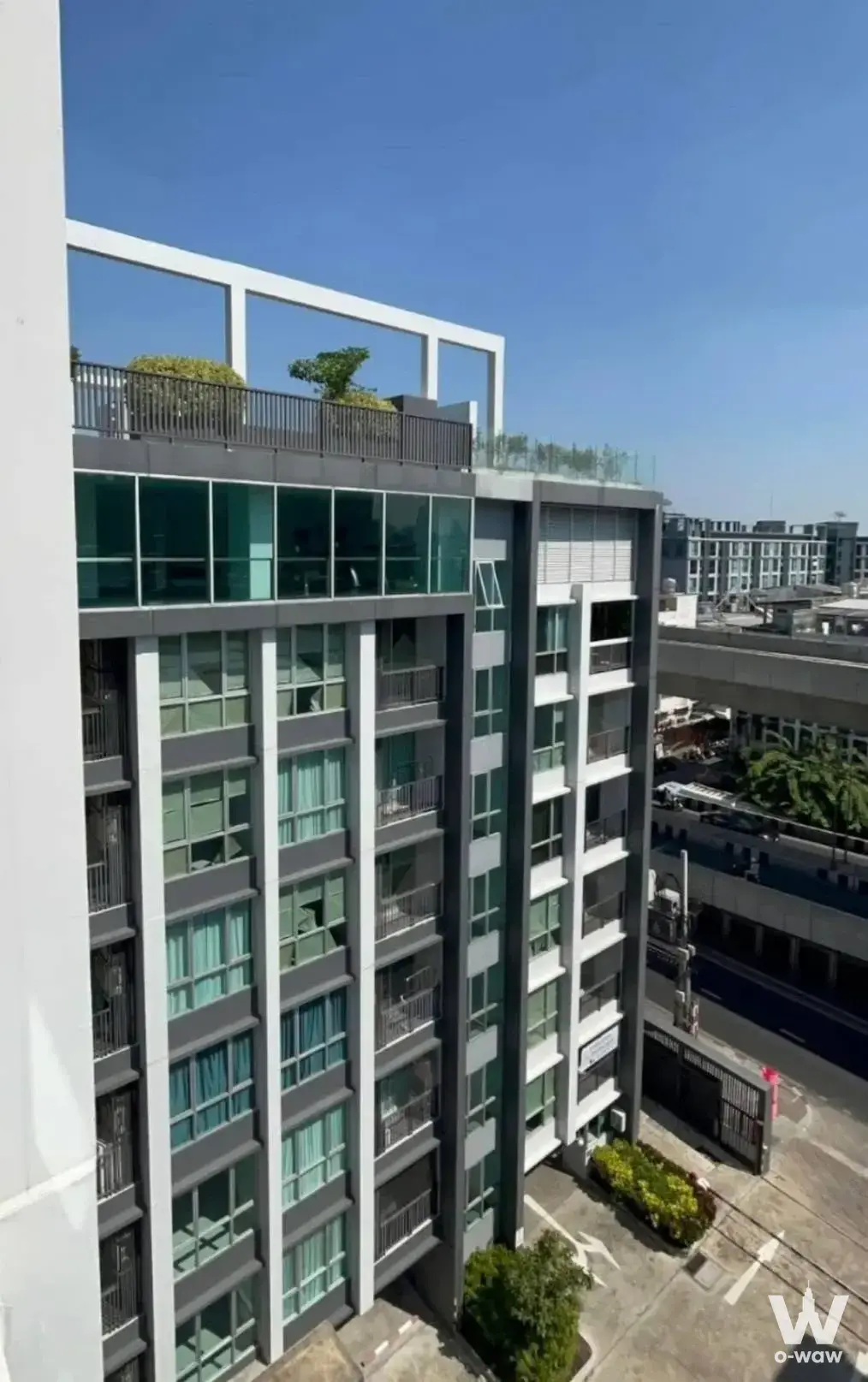 The Ville Express condo exterior with grey and white facade, vertical columns, and rooftop terrace