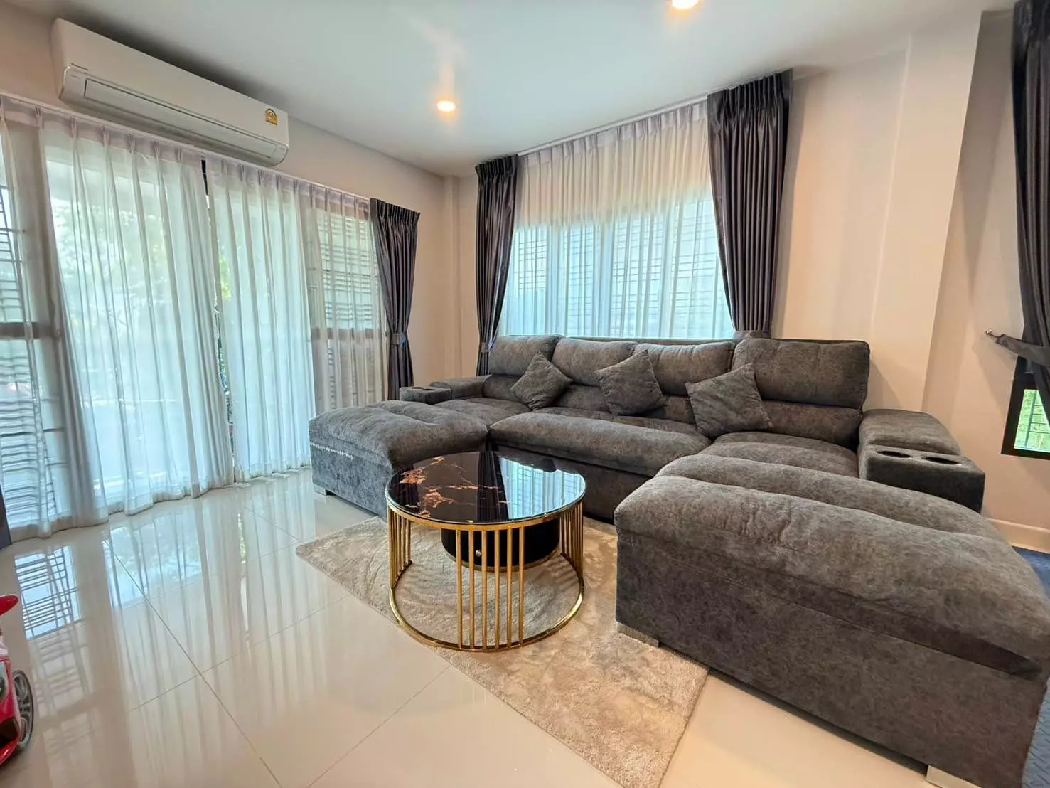 Modern living room in Centro Vibhavadi with L-shaped sofa, marble coffee table, and floor-to-ceiling windows