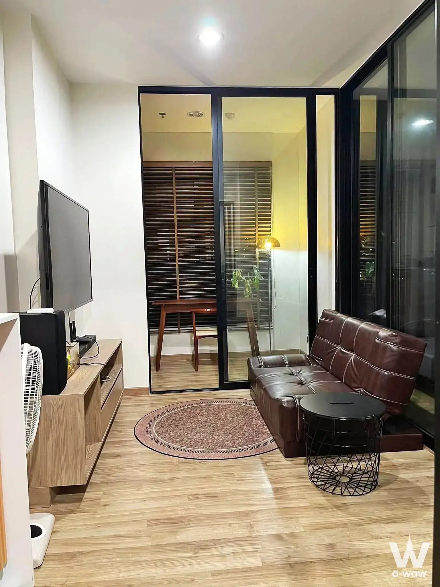 Bright living room in Niche MONO Charoen Nakhon with brown leather sofa and floor-to-ceiling glass doors