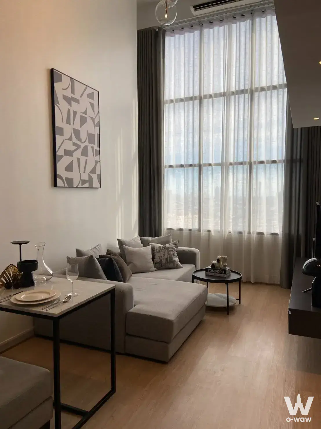 Living room in KnightsBridge Prime Sathon with L-shaped sofa, dining set, and abstract wall art