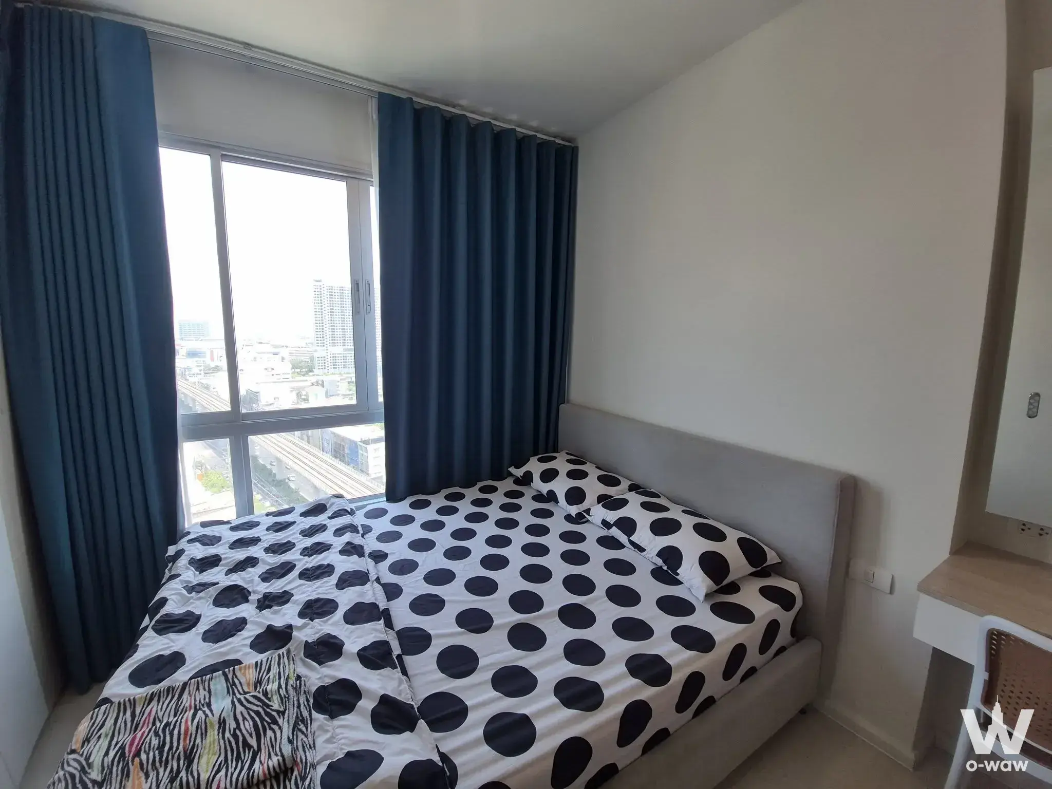 Bedroom in The Prodigy Condo for sale with a queen bed, navy curtains, and a view of the city and railway tracks