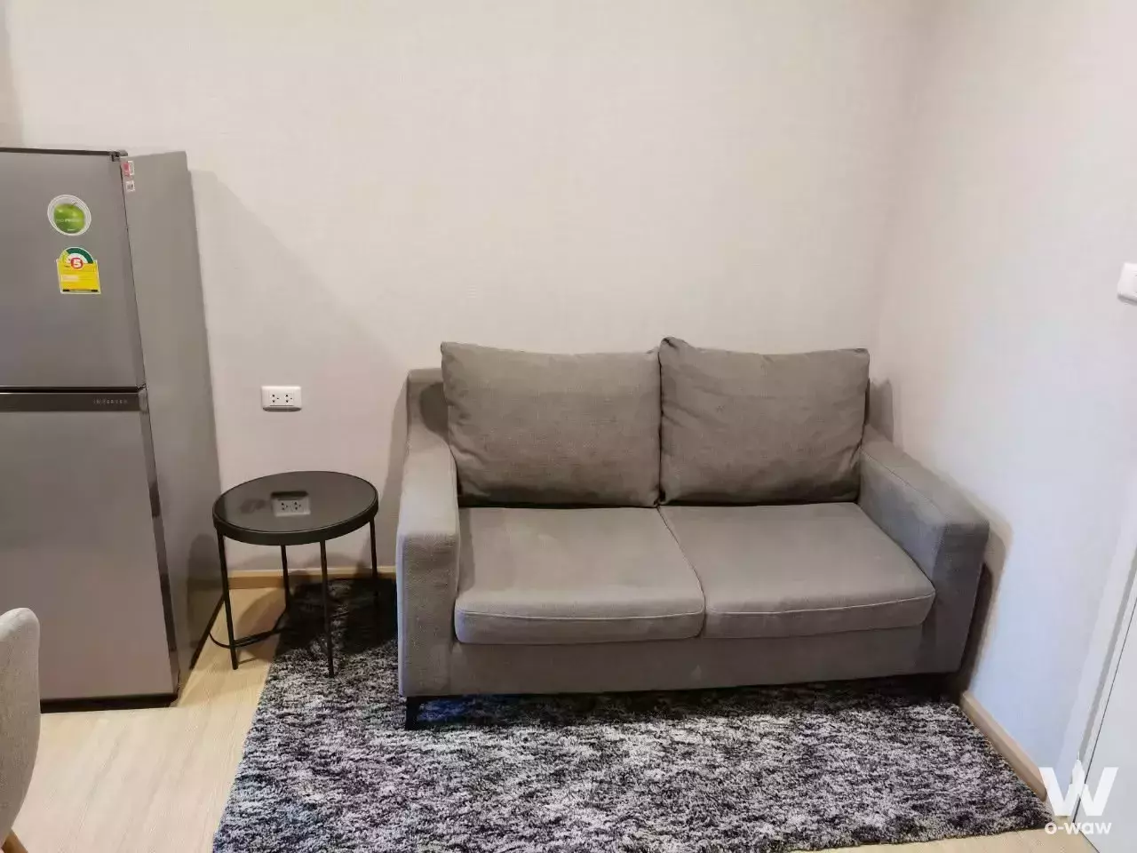 Compact furnished living corner in Plum Condo Pinklao 1-bed rental with grey sofa and wood laminate floors