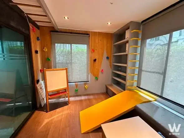 Playful kids playroom in a 3-bed house for rent in Mantana Bangna with climbing wall, yellow slide, and built-in shelves