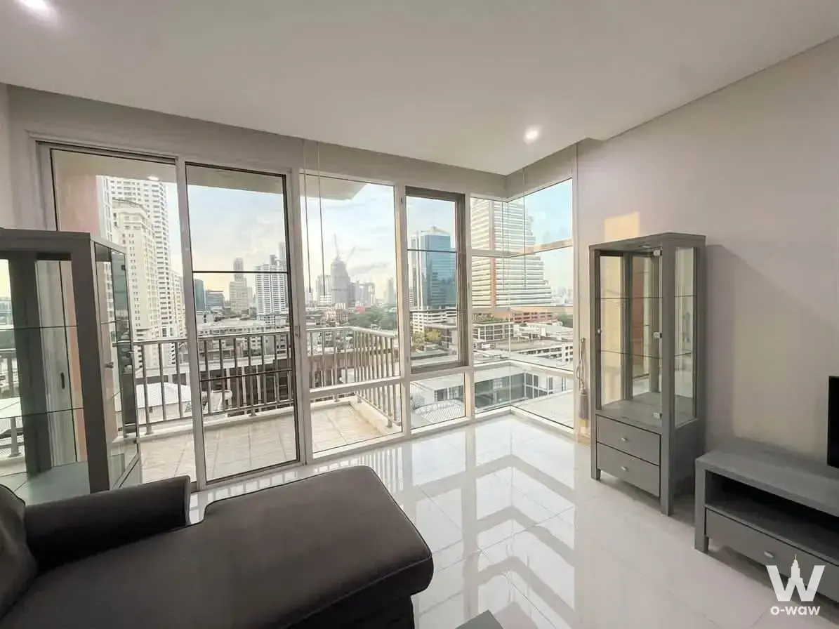 Living room in a 2-bed Fullerton Sukhumvit condo with corner glass doors offering city skyline views