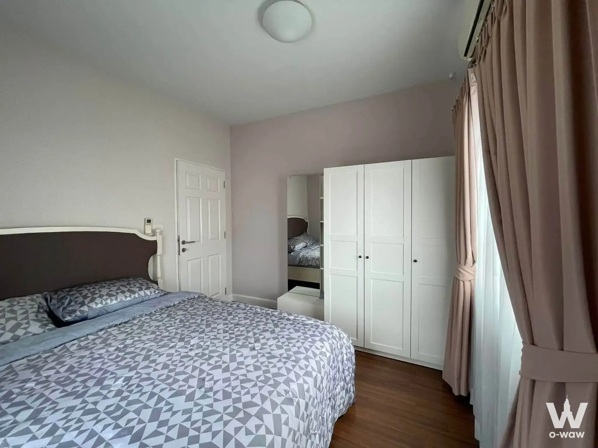 Furnished bedroom in Burasiri Panya-Indra condo with queen bed and large white wardrobe