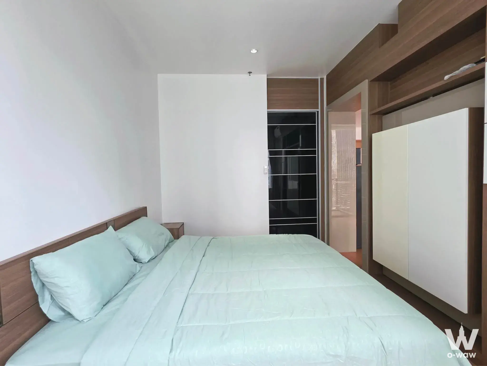 Mint green duvet on queen bed beside dark wood wardrobe in a Villa Ratchatewi house