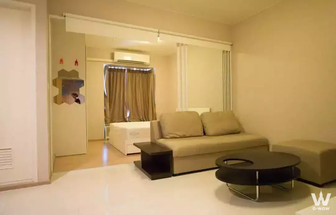 Compact 1-bed condo for rent in Fuse Mobius with beige sofa, black coffee table, and mirrored wall