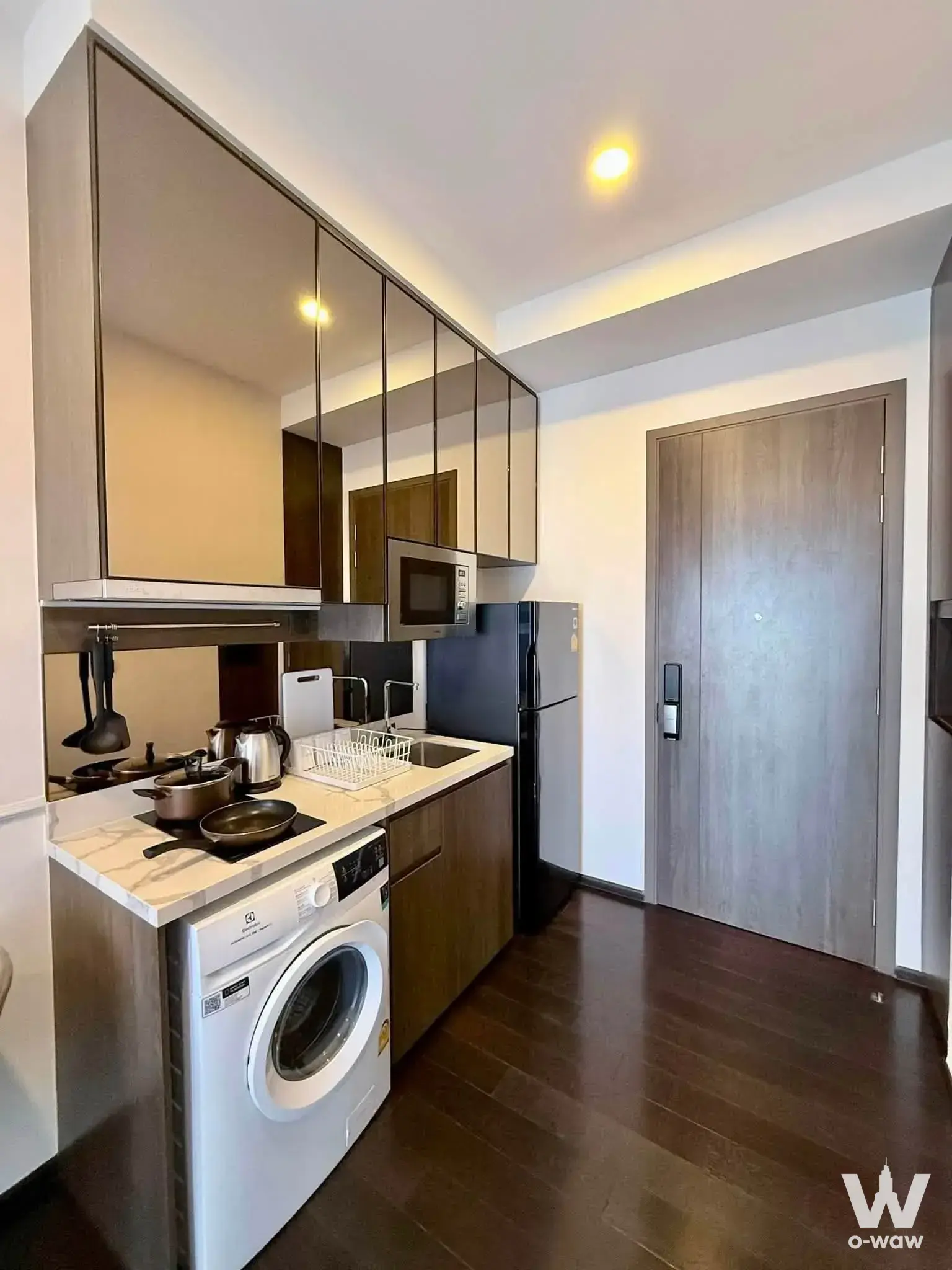 Compact kitchenette in a Park Origin Thonglor rental with mirrored cabinets, induction cooktop, and smart lock