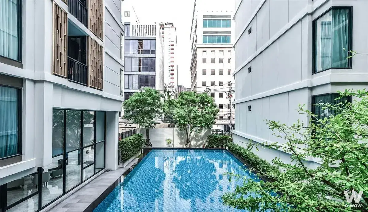 Narrow lap pool at Maestro 12 Ratchathewi condo surrounded by greenery and modern building facades