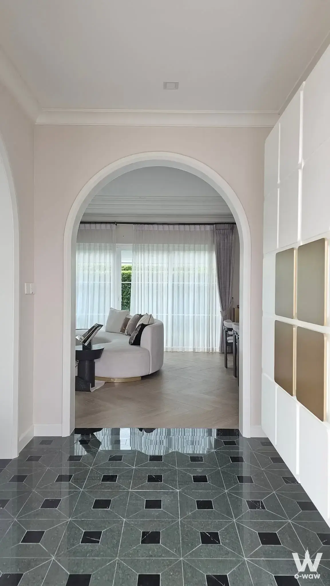 4-bed house for rent in Chaiyapruek Bangna showing an entry hallway with arched doorway and living room with curved sofa