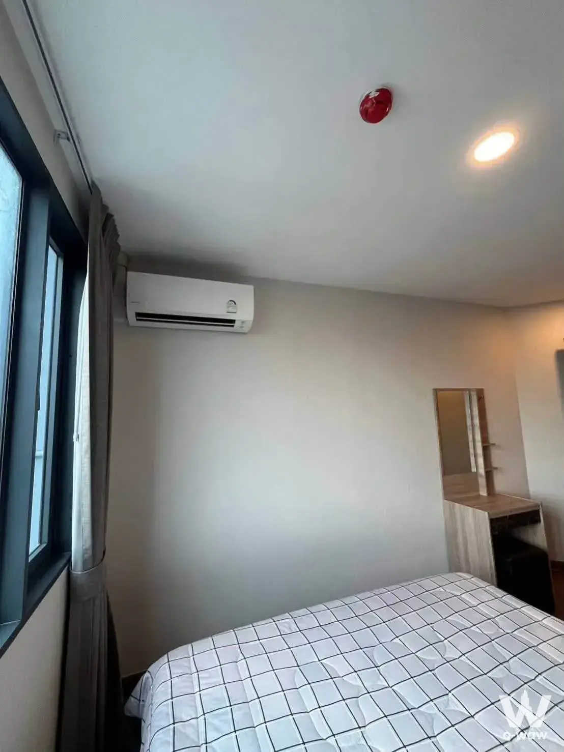 Bright bedroom with white walls, black grid duvet, and light wood vanity at Artisan Ratchada