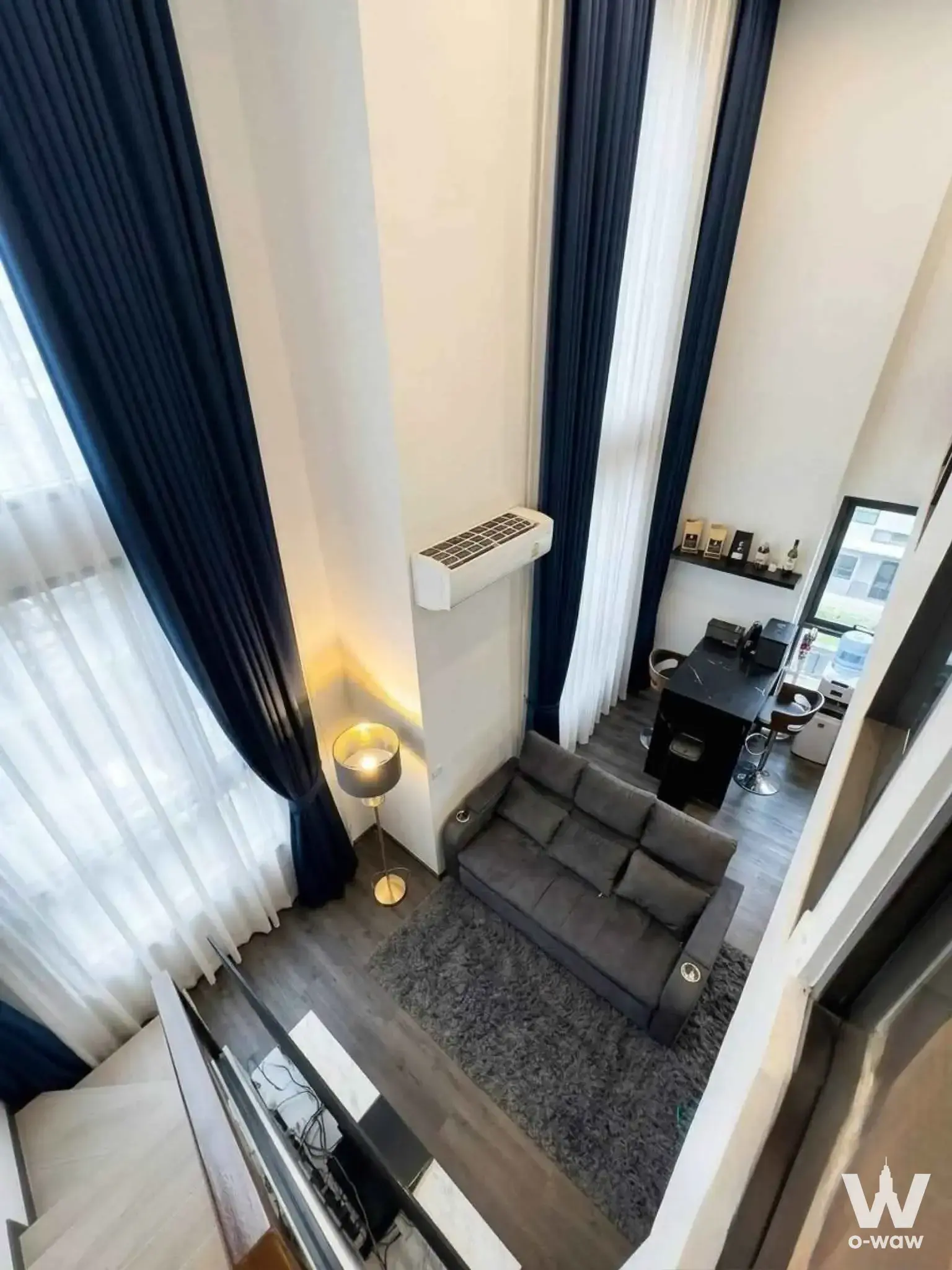 Loft-style 2-bed condo living room with navy drapes, grey sofa, and chrome bar stools at Centric Ratchayothin