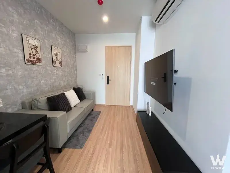 Grey sofa, stone accent wall, and TV console in a fully furnished Skyrise Avenue living room