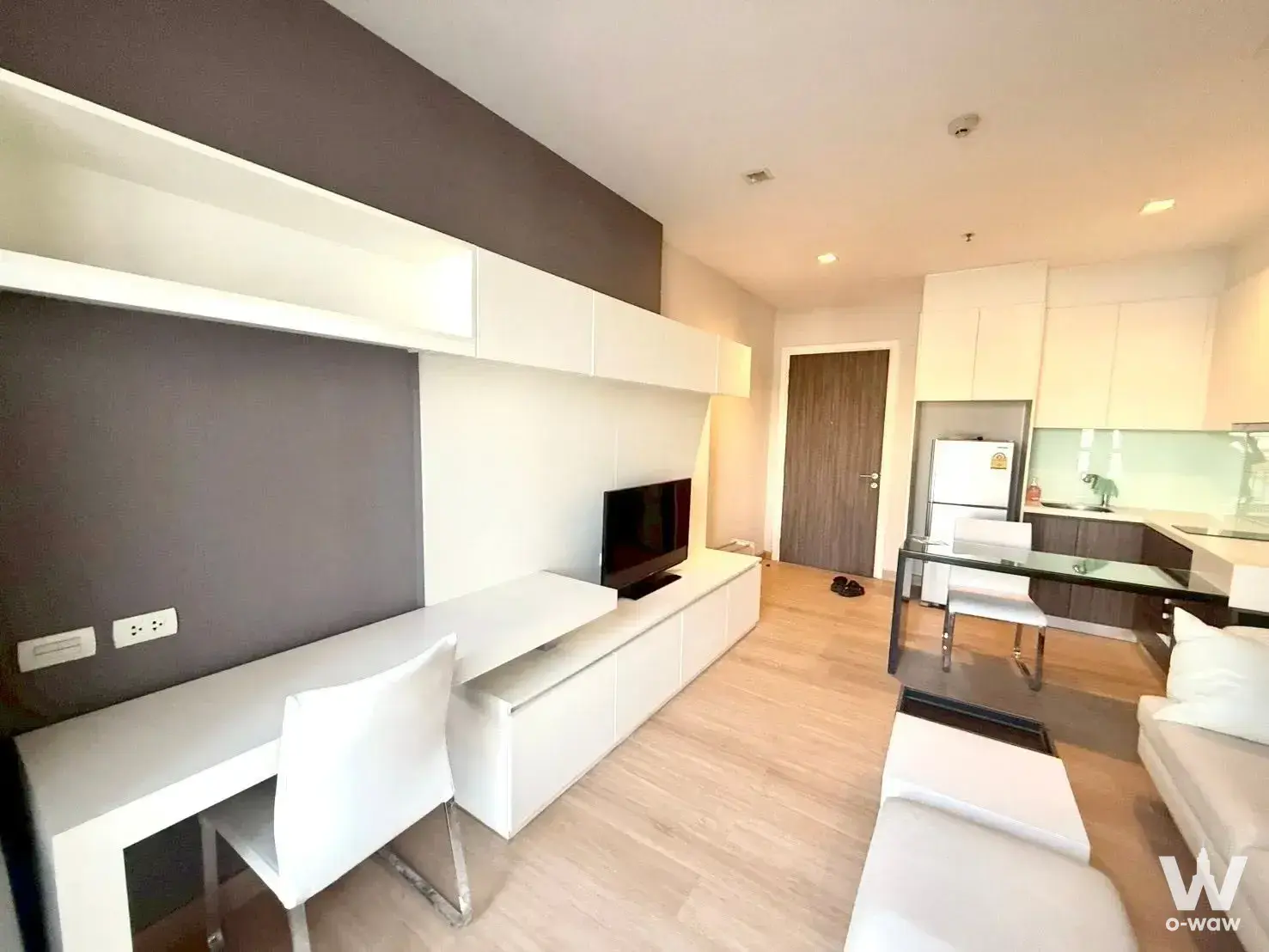 Open-plan studio with white built-in desk, dining table, and kitchen in Urbano Absolute
