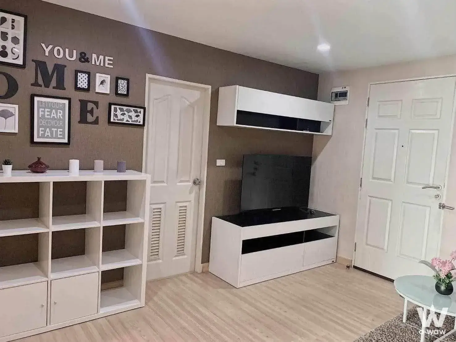 Living room in The Niche ID Ladprao 130 condo with taupe accent wall and white shelving unit