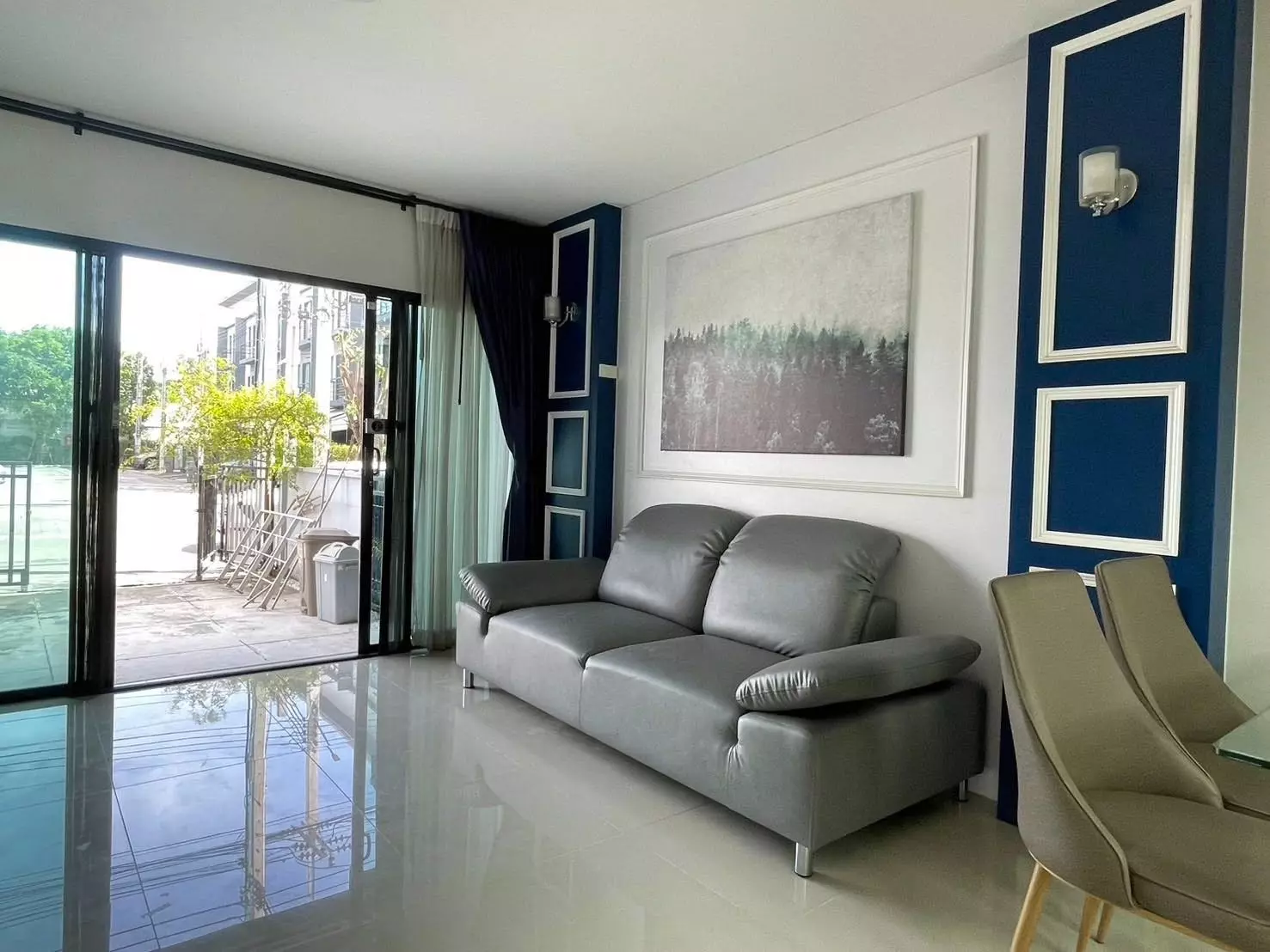 Modern living room with grey sofa and navy accent wall in Baan Klang Muang Rama 9