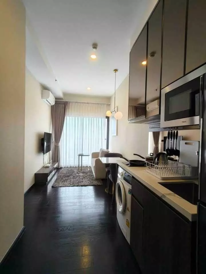 Open-plan living area in Park Origin Thonglor 1-bed condo with dark wood floors and kitchenette