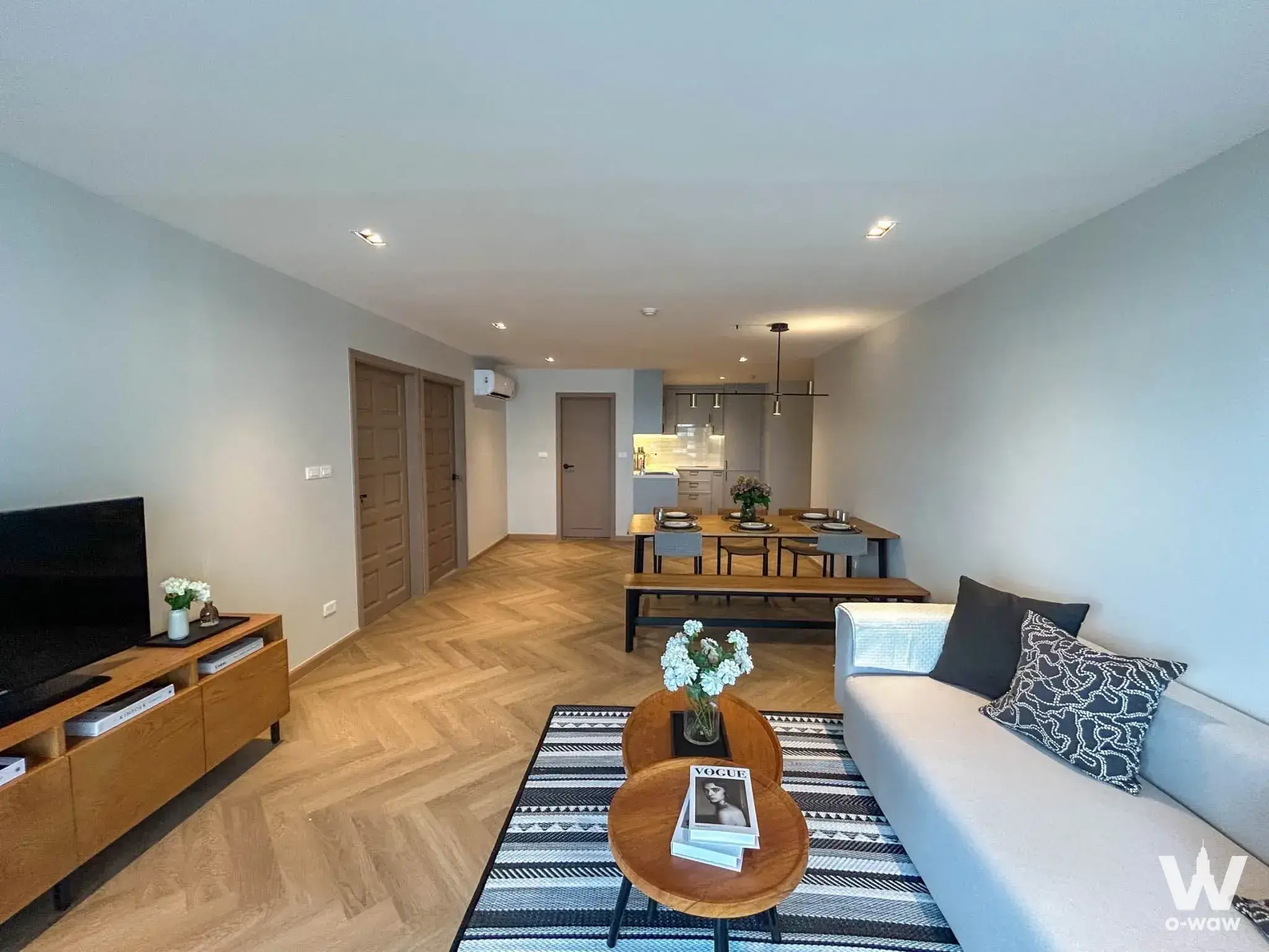 Open-plan living area with herringbone floors and dining set in a 2-bed Floraville condo for sale