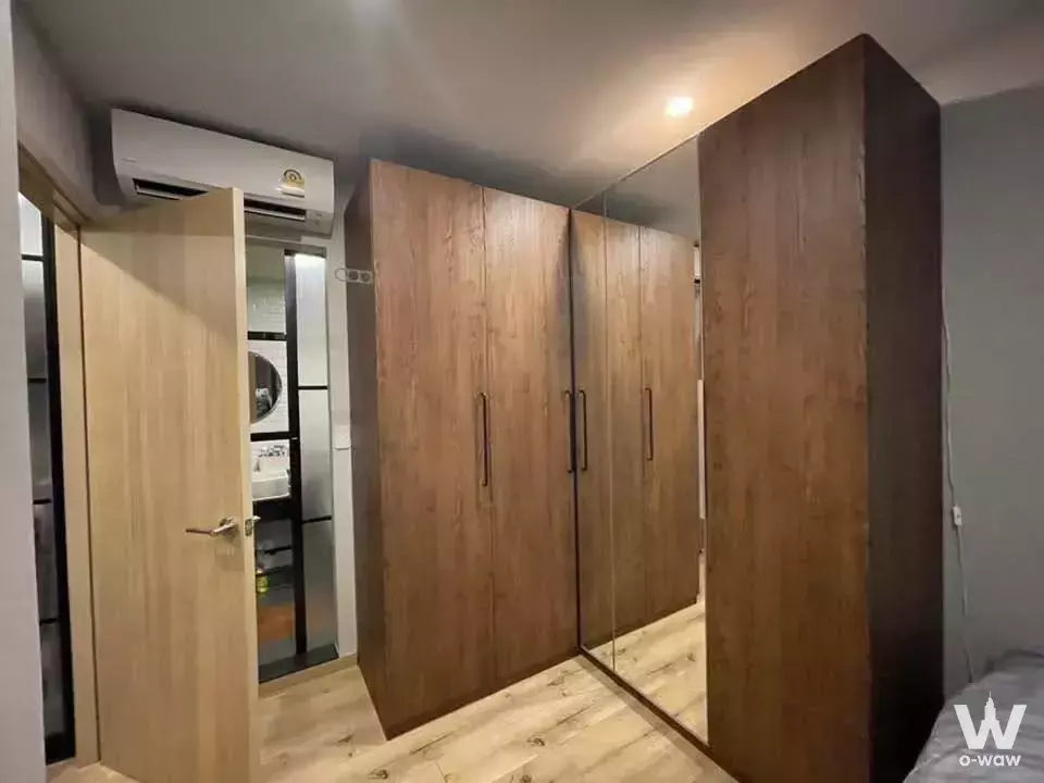Bedroom with built-in wardrobe, grey walls, and en-suite bathroom view in 2-bed condo for rent at Brix Condominium Charan 64