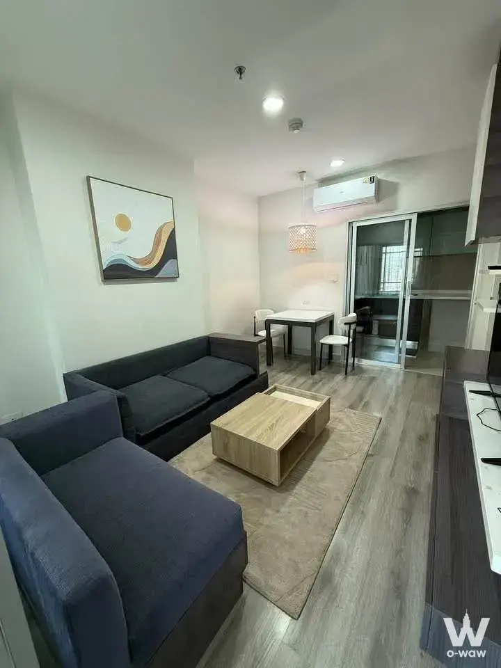 This 1-bed condo for rent at Centric Sathon-St Louis shows an open-plan living room with a sofa, dining set and balcony