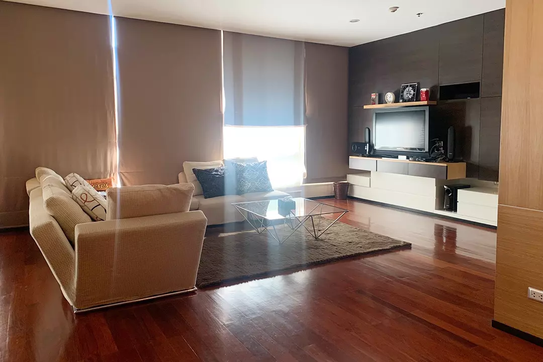 Modern living room with L-shaped sofa, glass coffee table, and hardwood floors in The Height