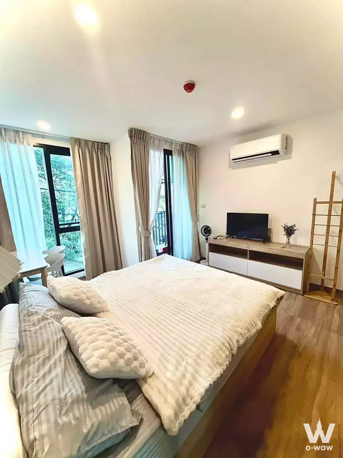 Cybiq Ratchada 32 bedroom with queen bed, media console, and floor-to-ceiling windows overlooking trees