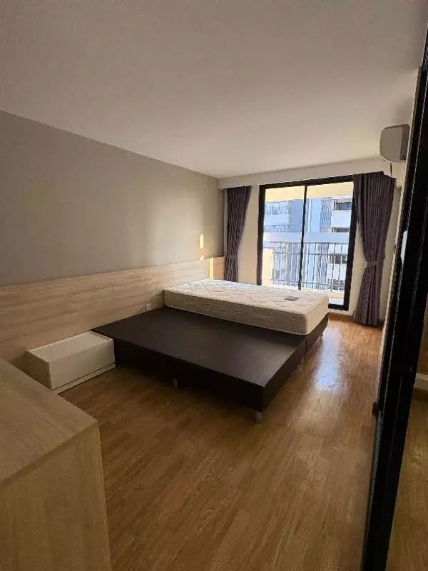 Bedroom in Level Bangna 1-bed condo with platform bed, wood laminate floors, and balcony access