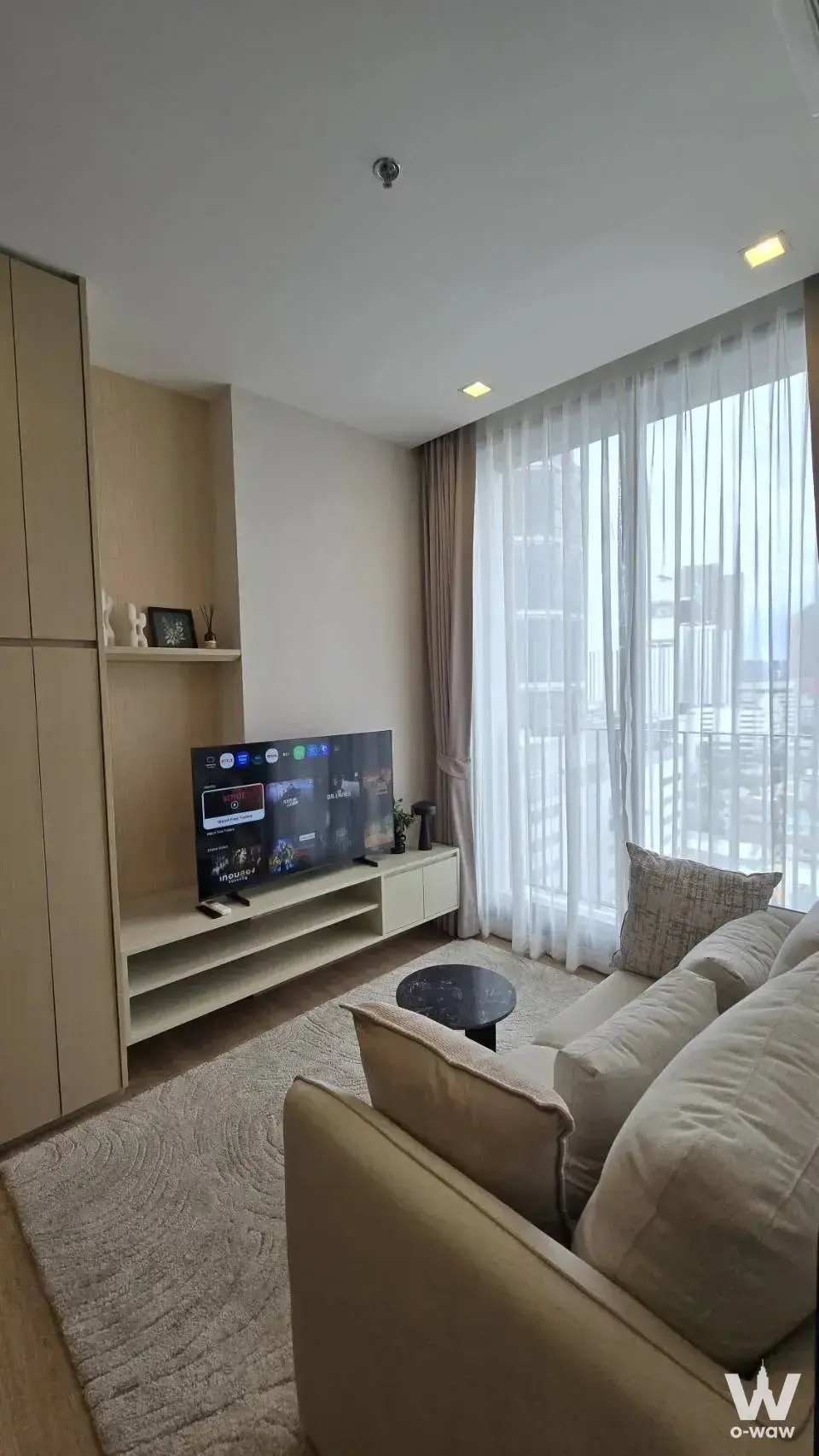 Bright 1-bed condo for rent in Noble Around Ari with beige sofa, built-in oak unit, and high-floor city views