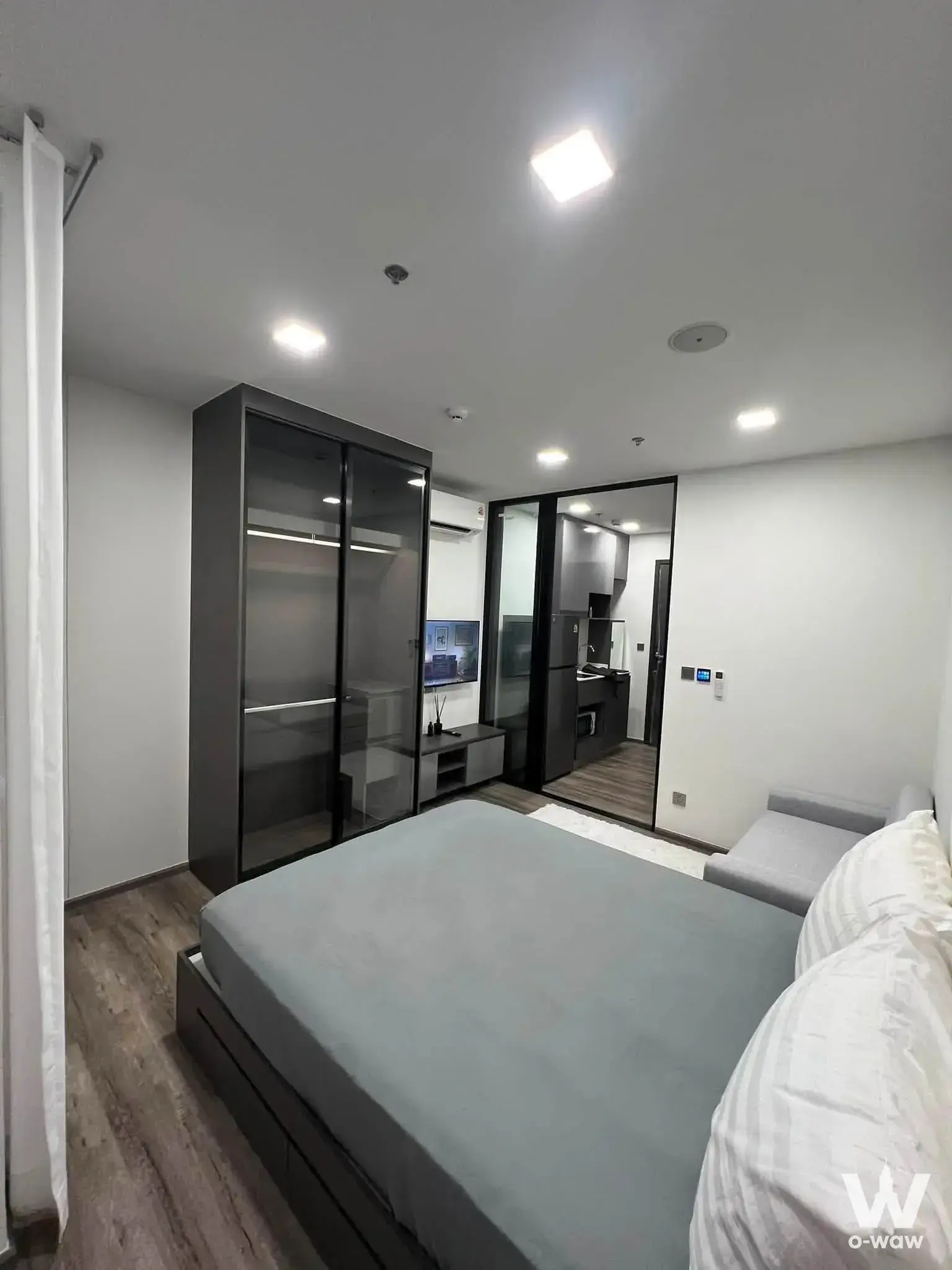 Bedroom in Modiz Vault Kaset Sripatum condo with dark wood bed frame and frosted glass wardrobe