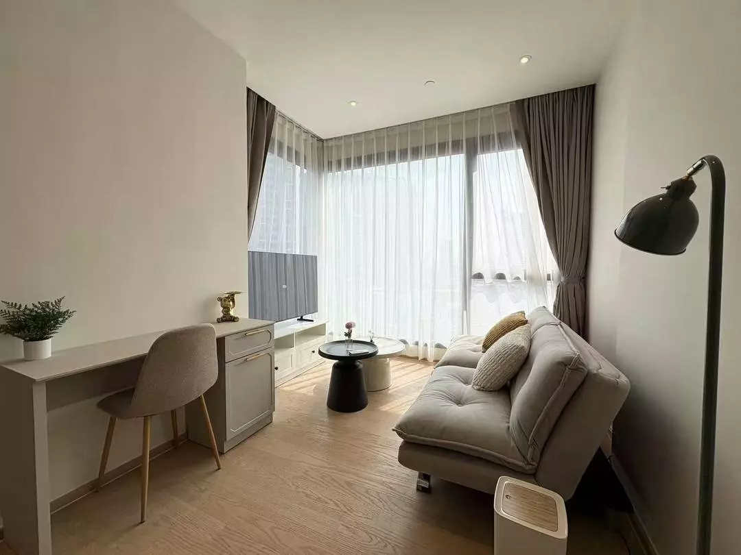 Bright 1-bed condo living room in ASHTON Asoke with oak floors, beige sofa, and floor-to-ceiling windows