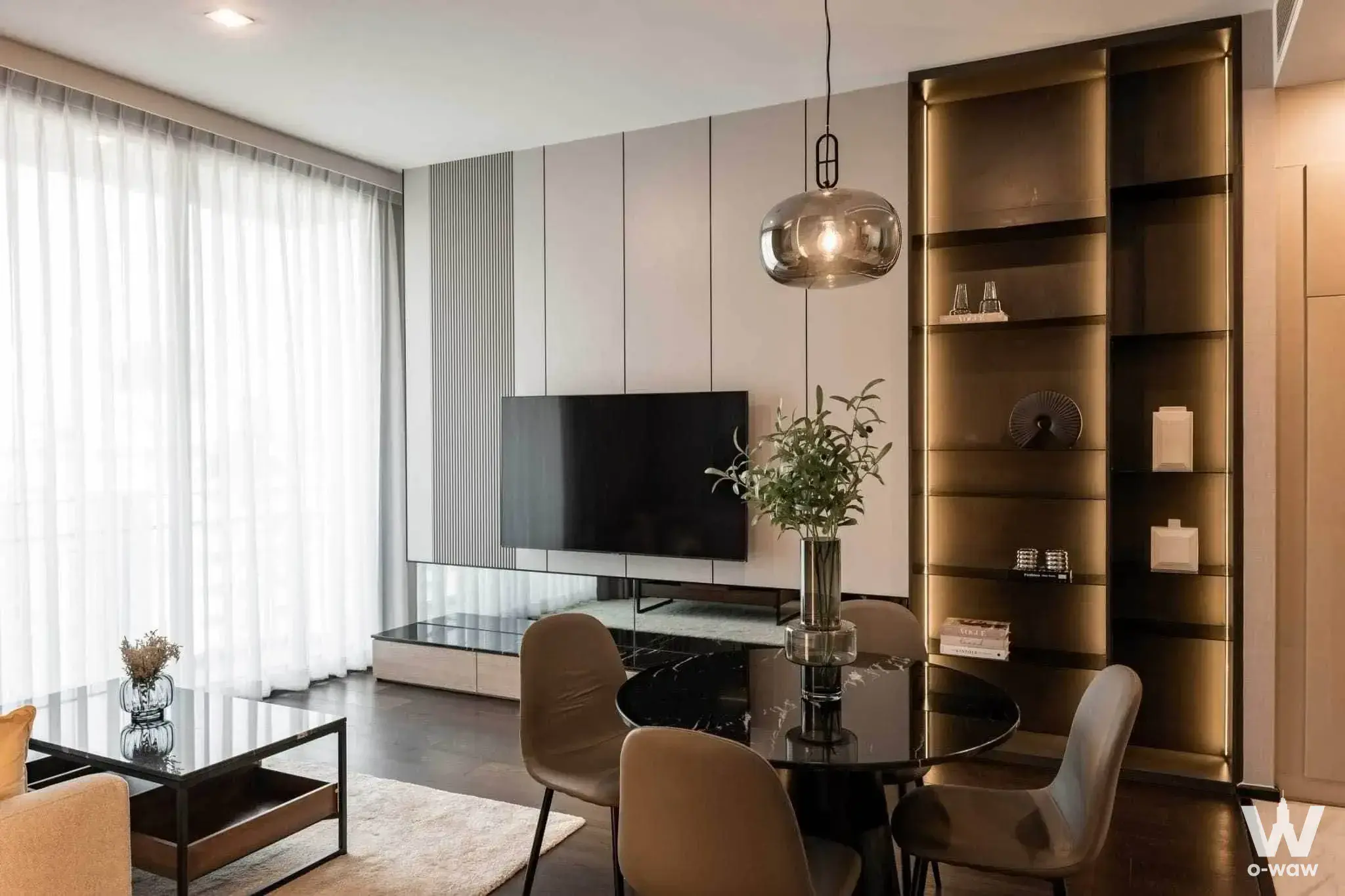 Luxury living area in LAVIQ Sukhumvit 57 with dark wood floors, a marble dining table, and built-in shelving