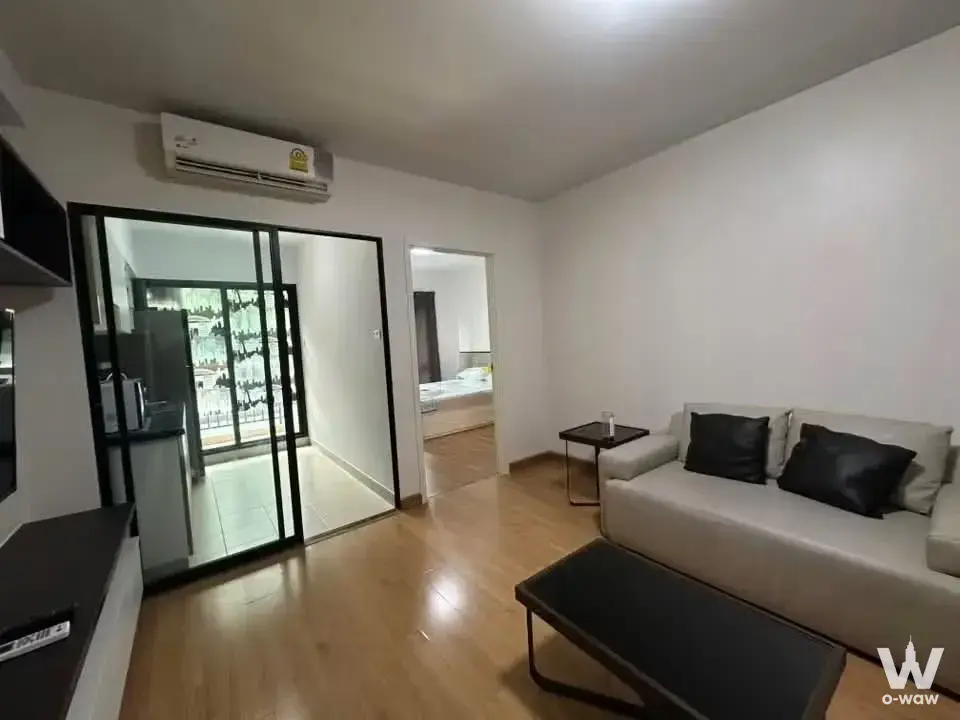 Grey sofa and glass partition doors in the living room of a 1-bed condo at Sukhumvit City Resort